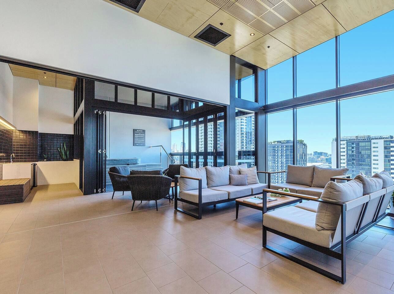 A modern living room with a sofa, chairs, a coffee table, and a view of the city through large windows.