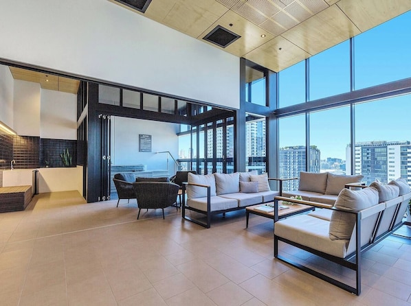 A modern living room with a sofa, chairs, a coffee table, and a view of the city through large windows.