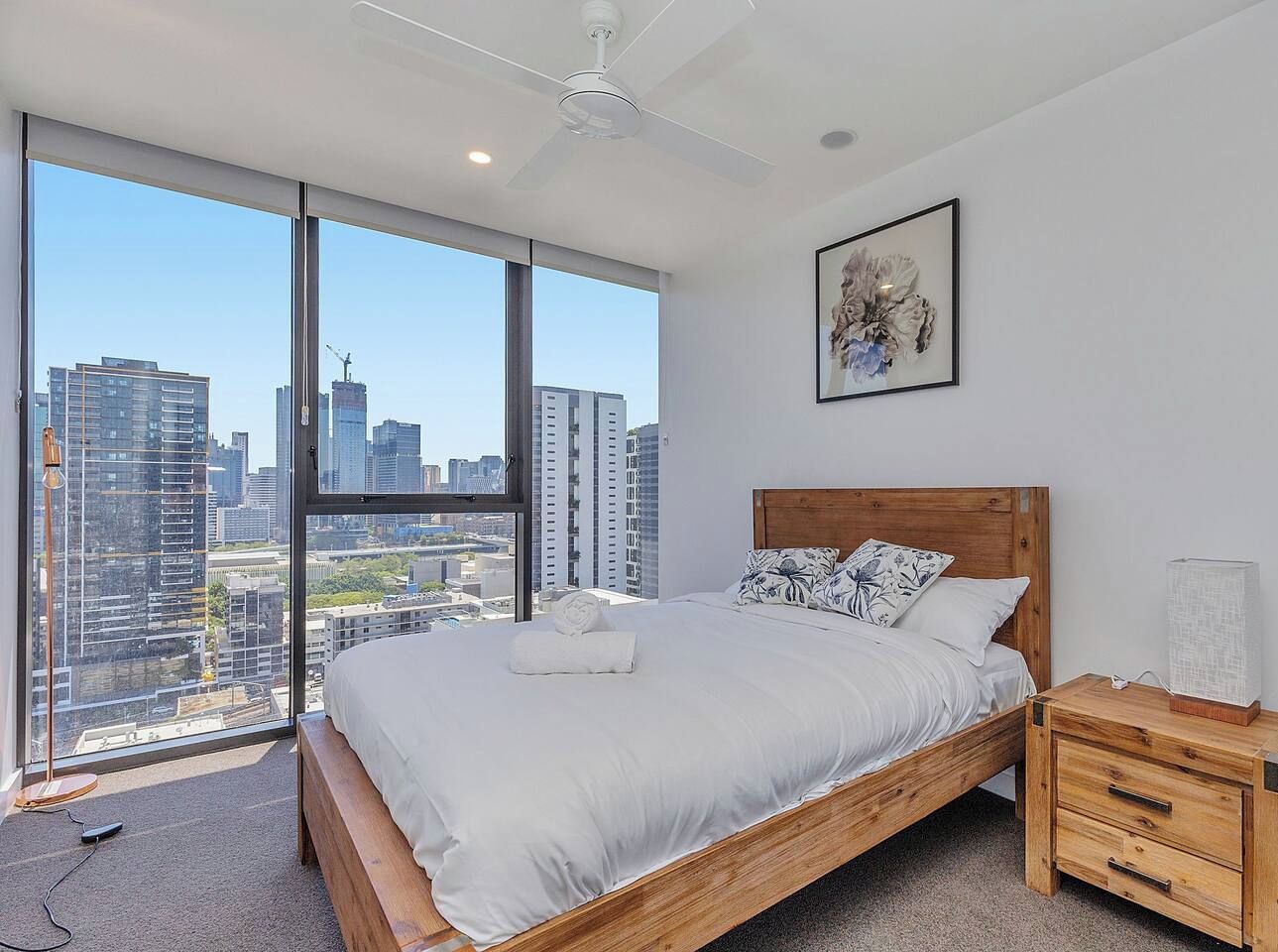 A bedroom with a large bed, wooden headboard, and a nightstand with drawers.