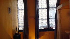 A bedroom with a bed, a nightstand, and a window with curtains. - Hôtel du Palais (Rouen)