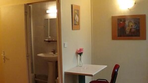 A bathroom with a sink and mirror, a small table with a vase of flowers, and a chair. - Hôtel du Palais (Rouen)