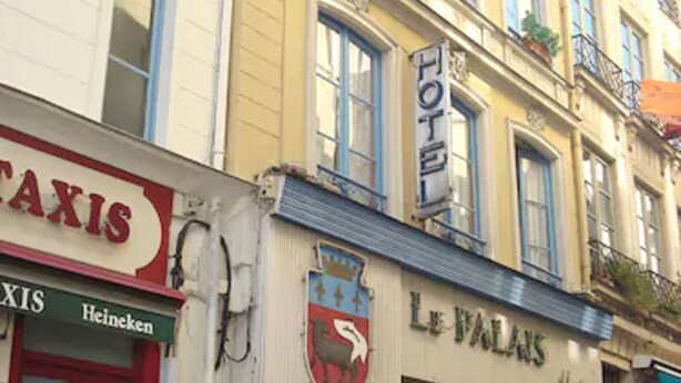 A building with a 'TAXIS' sign, a 'Heineken' sign, and a 'Le Palais' sign. - Hôtel du Palais (Rouen)
