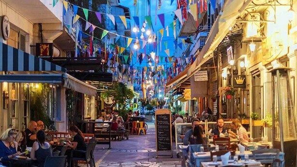 A narrow street lined with cafes and restaurants, decorated with colorful triangular flags. - City-Sea Fusion, Elegant Gem Minutes from the Beach (Kalamata)