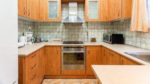 A kitchen with wooden cabinets, a stainless steel range hood, a microwave, and a toaster. - Zografou Hidden Gem - Athens Charming Home (Zografos)