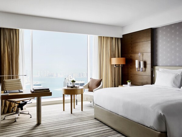 Une chambre d’hôtel avec un grand lit, un bureau, une chaise, une lampe et une vue sur la ville.