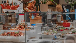 Un buffet proposant des fruits de mer, notamment des crevettes et du homard, ainsi qu’une plante décorative.