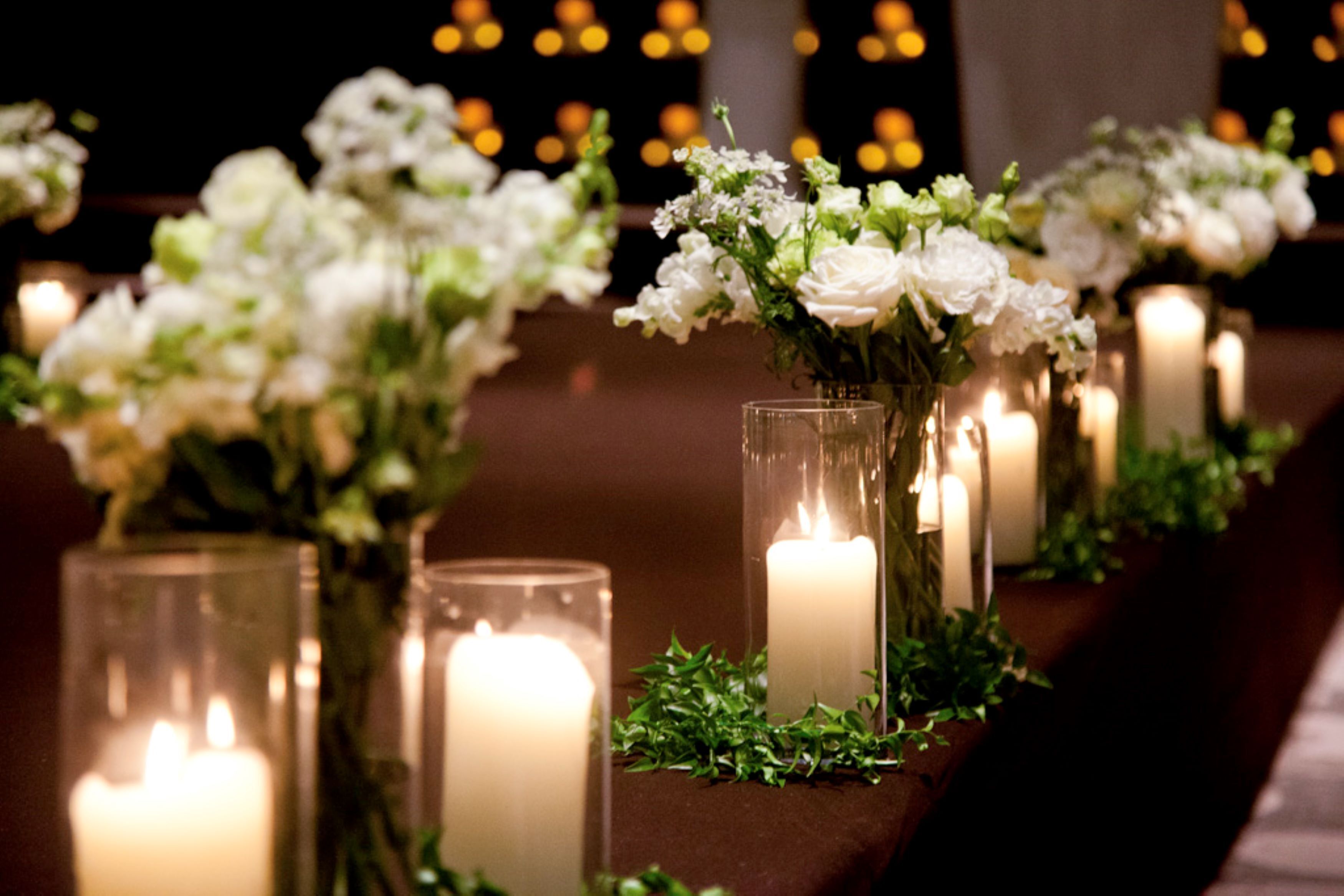 Varias mesas con velas y flores blancas, probablemente en un hotel.