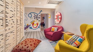Una sala de estar moderna con un revestimiento de listones de madera, un sillón rojo, un sillón amarillo y una alfombra colorida.