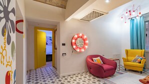 Una sala de estar moderna con piso estampado con motivos de estrella, un sillón rojo, un sillón amarillo y una lámpara fijada a la pared.