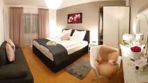 Moderni hotellihuone, jossa on sänky, sohva, tuoli, työpöytä ja suuri peili.