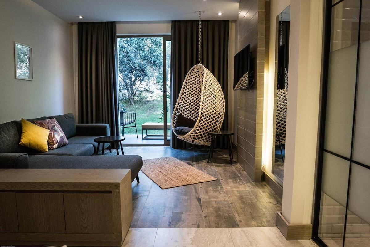 Una sala moderna con un sofá, un sillón colgante y vistas al exterior.