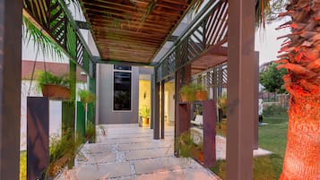 Un sendero cubierto con escalones de piedra y plantas en macetas, que conduce a la entrada de un edificio.
