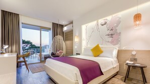 A modern hotel room with a large bed, a desk, and a balcony with outdoor furniture.