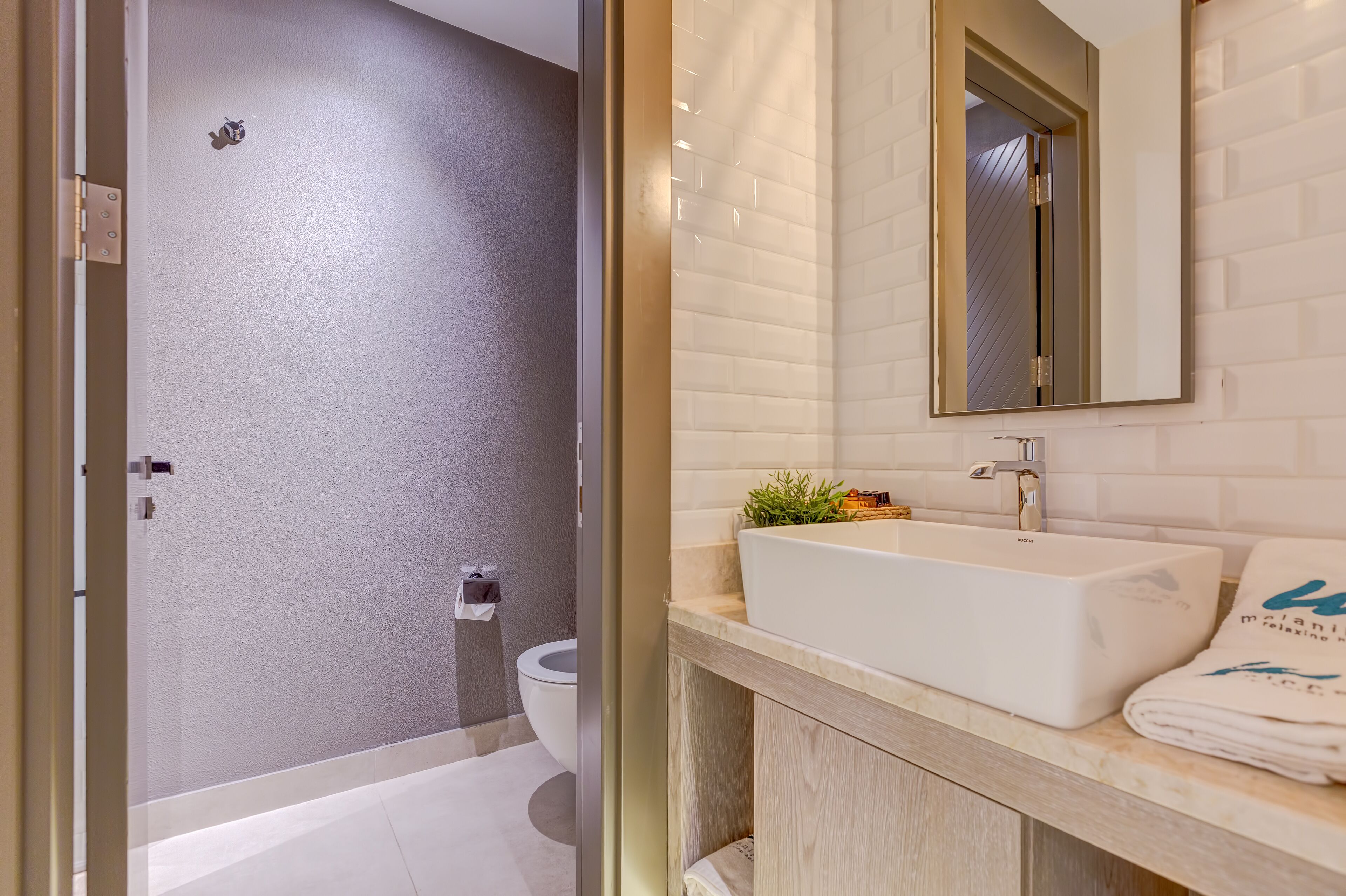 A modern bathroom with a white sink, a mirror, and a towel on the counter.