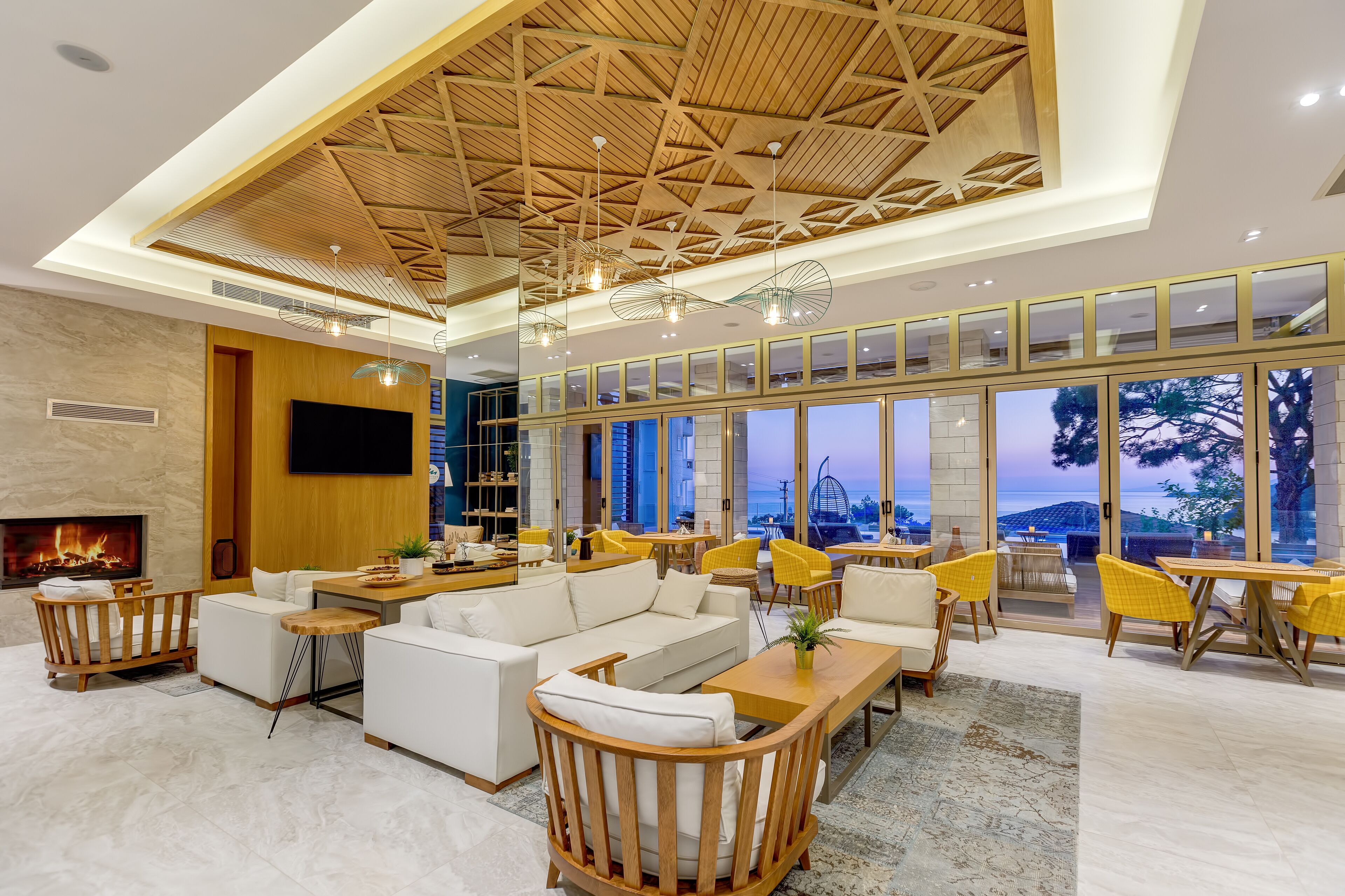 Een ruime lobby met een hoge plafond, een open haard, comfortabele zitplaatsen en grote ramen met uitzicht op de omgeving.