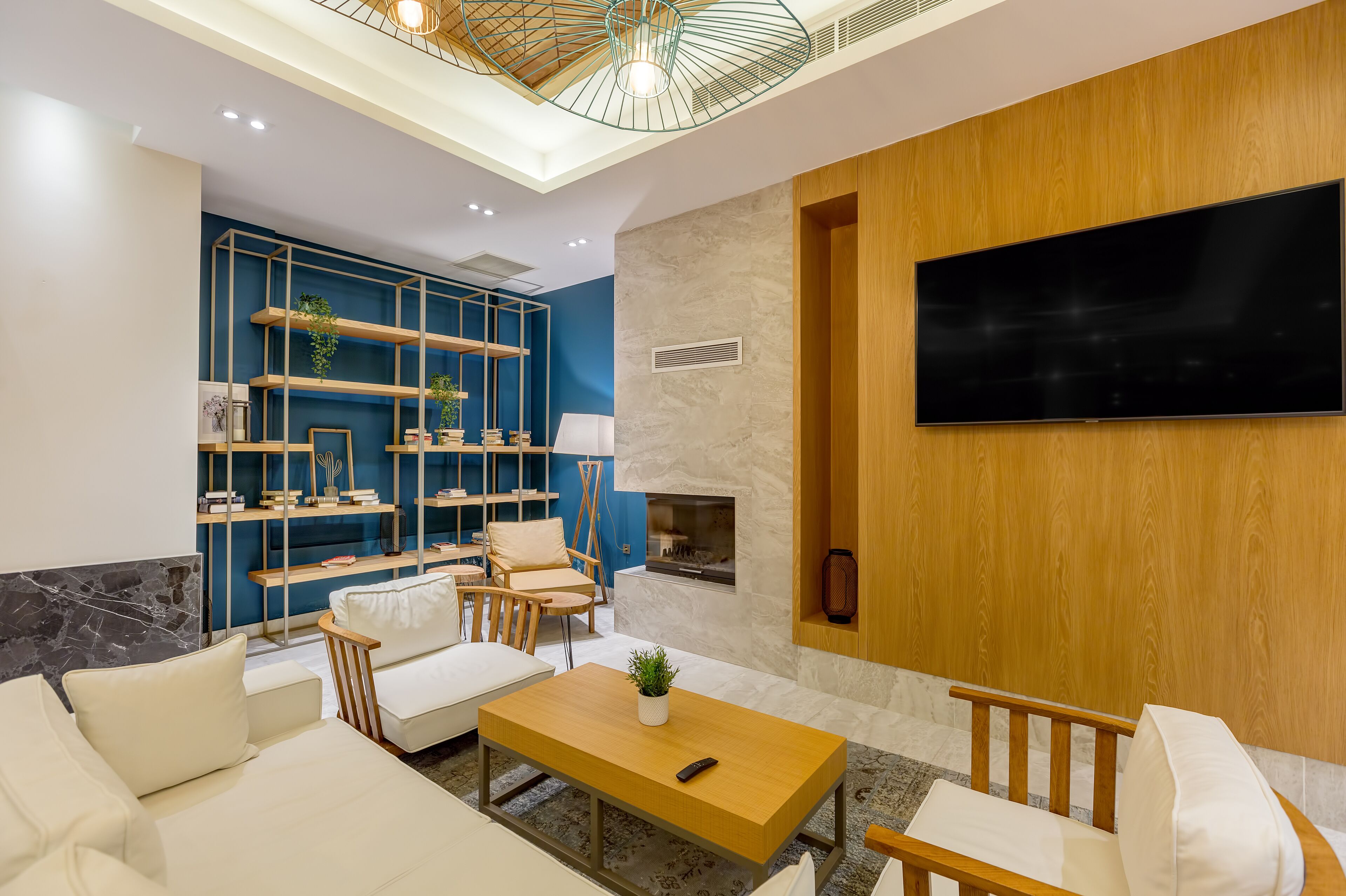 Una sala de estar moderna con televisor, sofá, mesa de centro y un estante azul con plantas.
