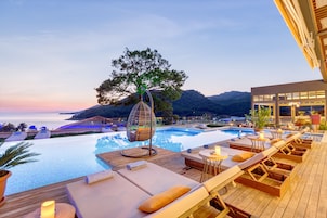 Una piscina al aire libre, sombrillas, sillones reclinables de piscina