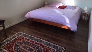 Een slaapkamer met een bed, nachtkastje, lamp en raam.