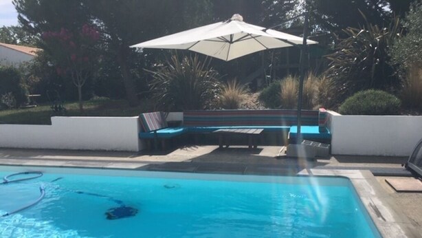 Een zwembad met ligbedden en een parasol.