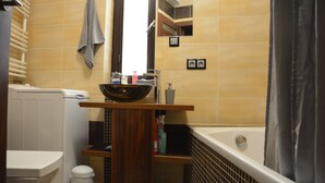 A bathroom with a bathtub, a toilet, a sink with a mirror, and a towel rack. - Labo Apartment Towarowa Kercelak (Warsaw)