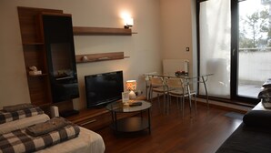A modern hotel room with a flat-screen TV, a glass dining table, and a sofa. - Labo Apartment Towarowa Kercelak (Warsaw)