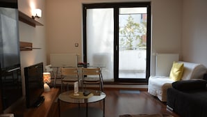 A modern living room with a sofa, a TV, a dining table with chairs, and a sliding glass door to the outside. - Labo Apartment Towarowa Kercelak (Warsaw)