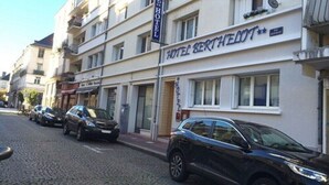A hotel named "HOTEL BERTHAELOT" with a signboard, parked cars, and a cobblestone street. - Hotel le Berthelot (Tours)