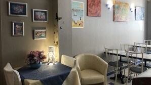 A dining area with a table set for two, chairs, and wall art. - Hotel le Berthelot (Tours)