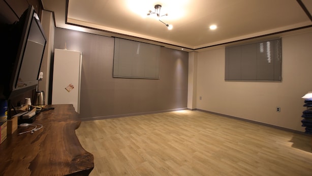 A room with a wooden desk, a white refrigerator, and two windows with blinds. - I Hotel&Motel (Pyeongtaek)