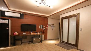 A hotel room with a wooden wall, a flat-screen TV, a small desk with a chair, a mini-fridge, a microwave, a coffee maker, and a sliding door to the bathroom. - I Hotel&Motel (Pyeongtaek)