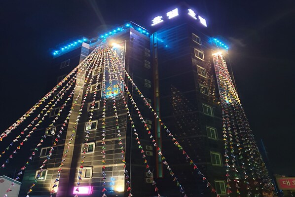 A tall building with multiple floors, each illuminated by bright lights. - I Hotel&Motel (Pyeongtaek)