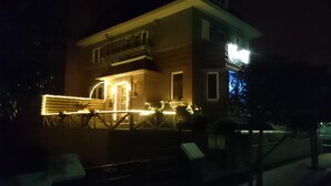 Un edificio de dos pisos con balcón y entrada iluminada.