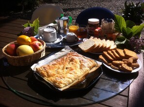 Bandeja de desayuno con un pastel, pan, galletas y una cesta de frutas.