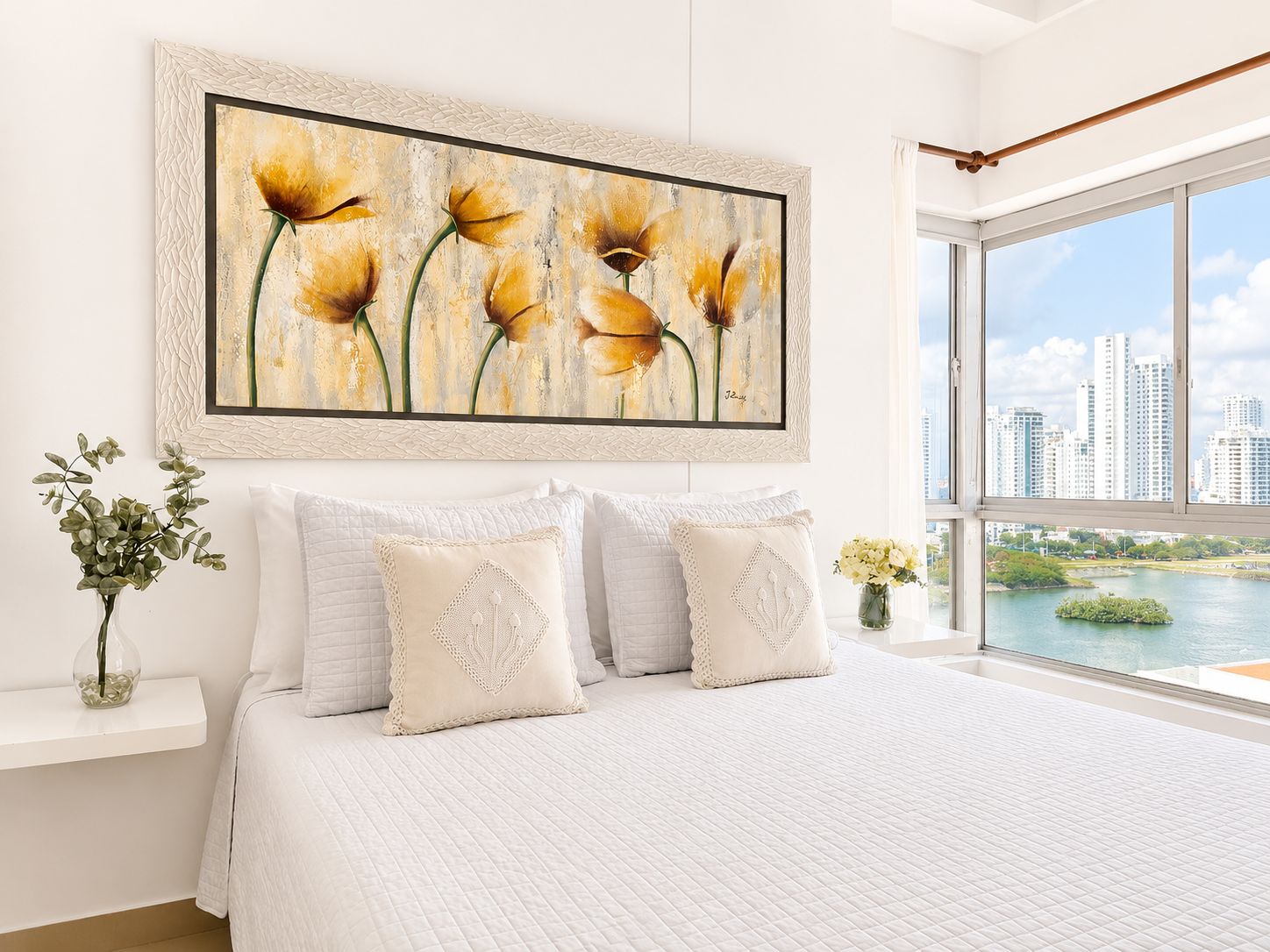 Un dormitorio con un ventanal grande, una cama con ropa de cama blanca y un cuadro de flores en la pared.