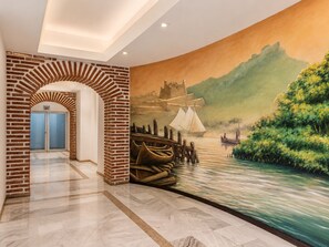 A hallway with a brick archway, a mural of a river scene, and a door with blue frosted glass.