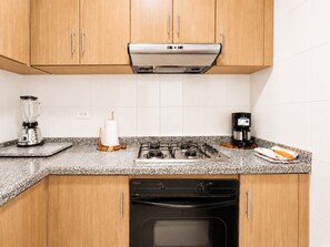 A kitchen with wooden cabinets, a gas stove, a coffee maker, a blender, and a paper towel holder.