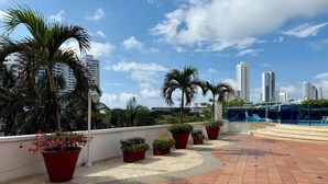 A rooftop terrace with potted plants, a tiled floor, and a view of tall buildings in the background. - Charming • Lovely view • Beach • Pool 1304 (Cartagena)