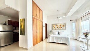 A modern bedroom with a bed, a ceiling fan, and a view of the city through large windows. - Charming • Lovely view • Beach • Pool 1304 (Cartagena)