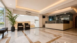 Een moderne lobby met een receptiebalie, een zithoek en een grote potplant.