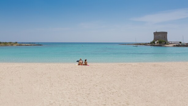 Ein Strand mit einem Turm im Hintergrund.