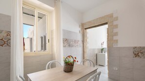 A dining area with a wooden table, white chairs, and a wicker basket with flowers. - Tenuta Fioravante (Porto Cesareo)