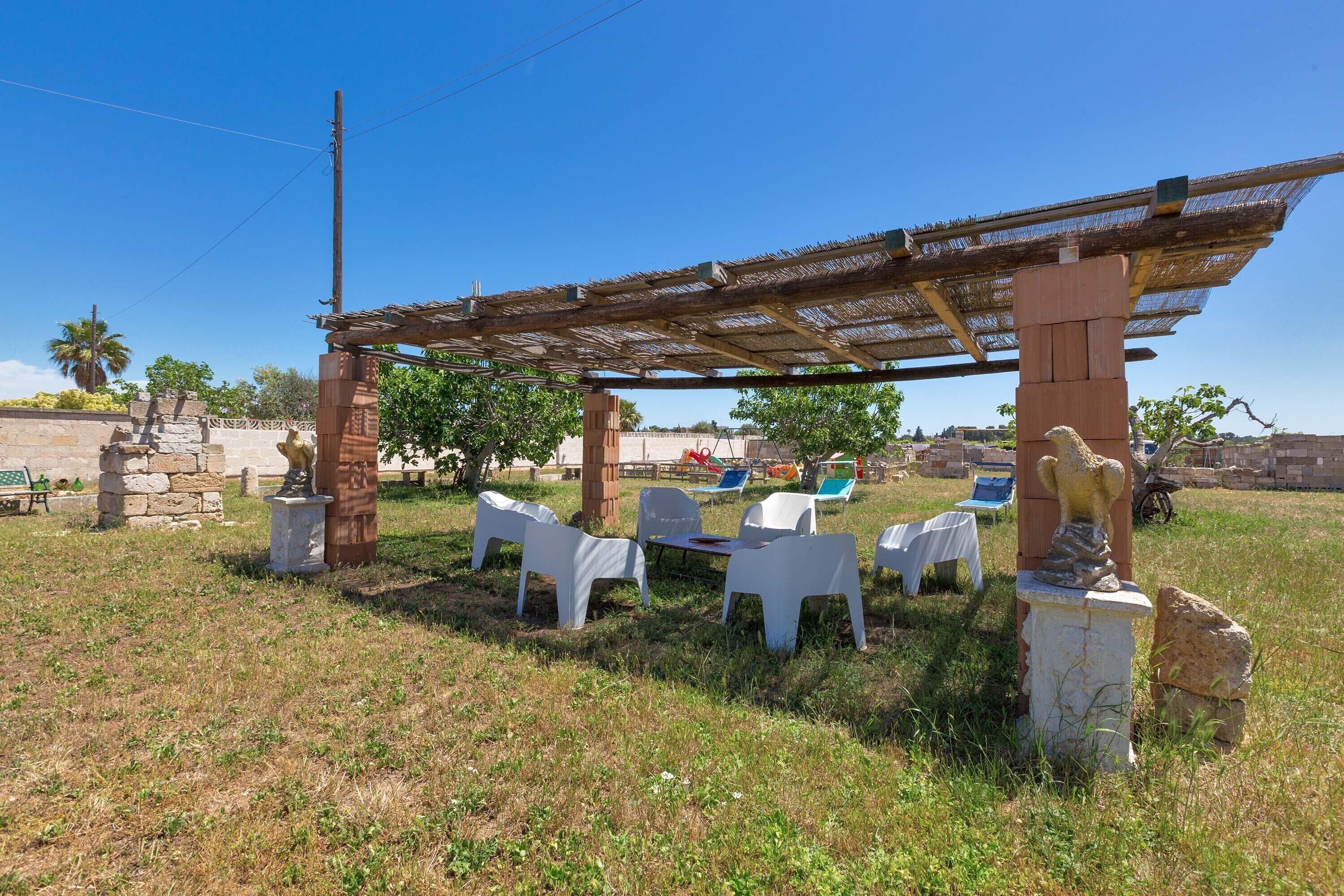 An outdoor seating area with white plastic chairs and a pergola structure.