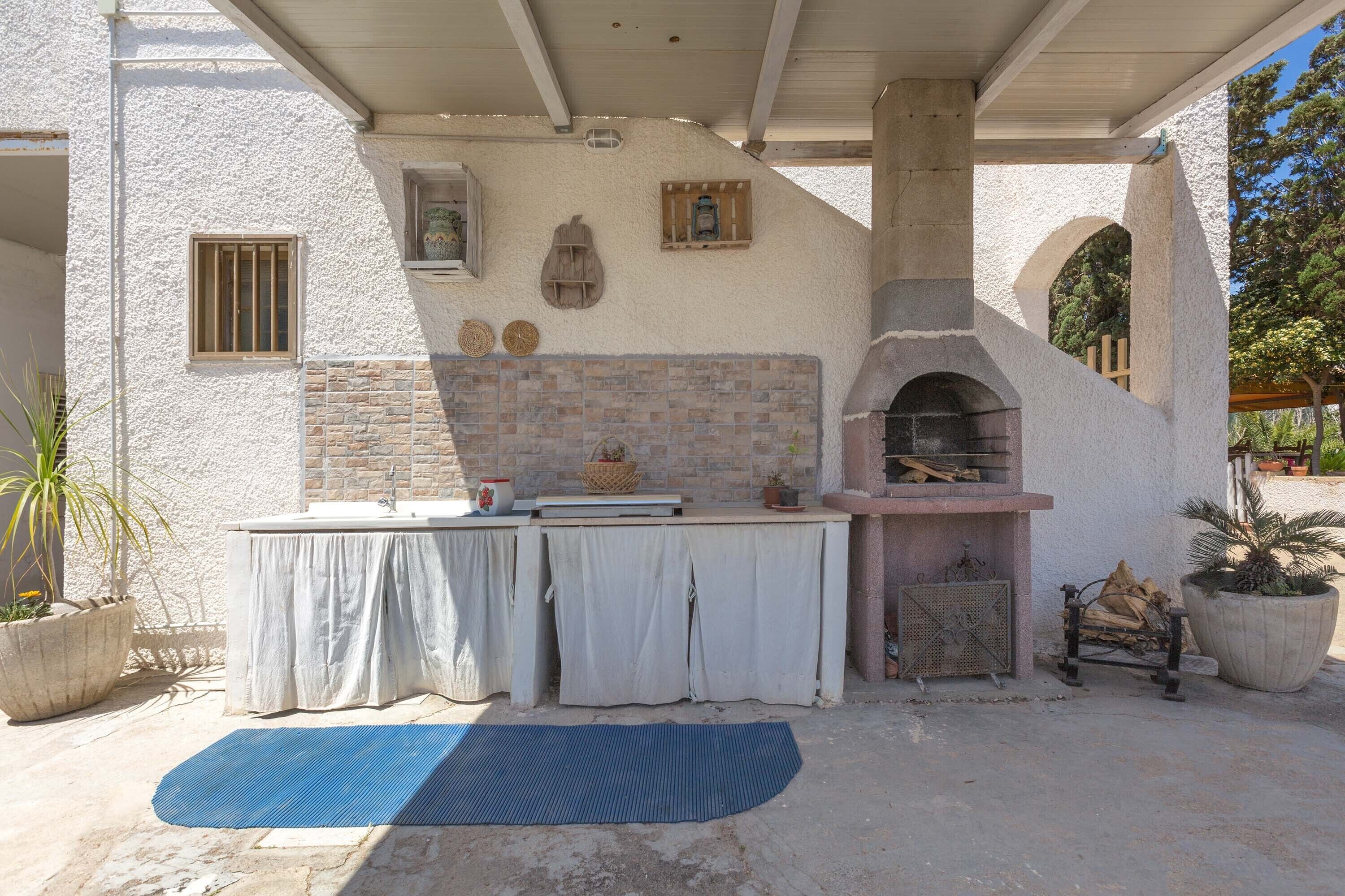 An outdoor kitchen area with a stone oven, a sink, and a table with a cloth cover.