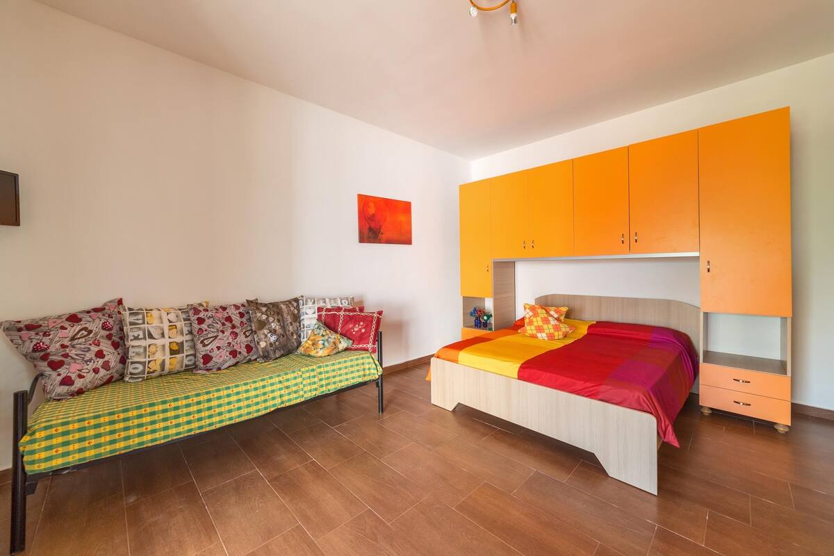 A bedroom with a bed, a sofa, and a wardrobe.