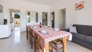A dining area with a checkered tablecloth, wooden chairs, and a grey sofa. - Villa Spiaggia degli Angeli (Porto Cesareo)