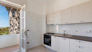 A kitchen with white cabinets, a stove, and a sink. - Villa Spiaggia degli Angeli (Porto Cesareo)