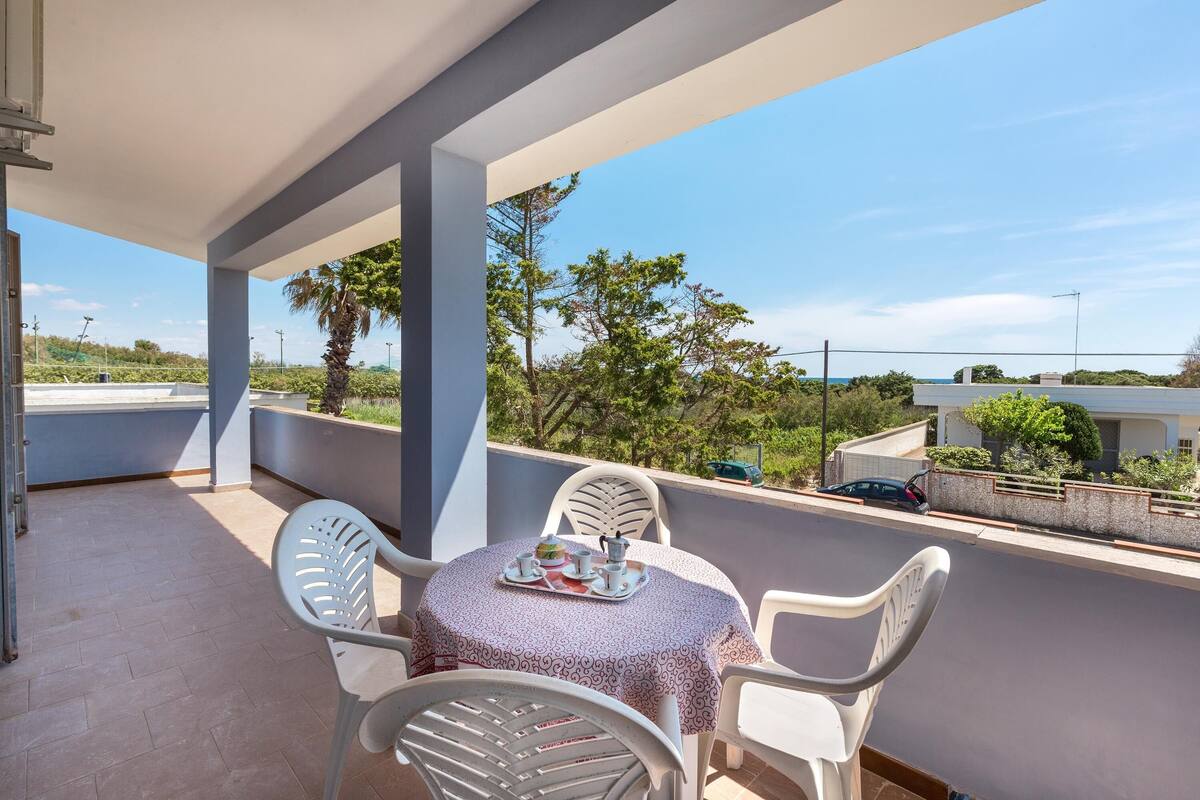 Ein Balkon mit einem Tisch für zwei Personen, mit Blick auf eine Wohngegend mit Bäumen und Häusern.