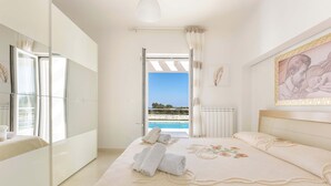 A bedroom with a large bed, a view of the sea, a balcony, and a large mirror. - Villa Specchia (Carovigno)