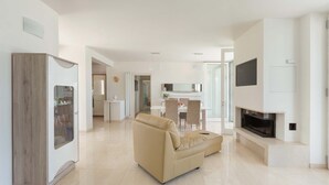 A modern living room with a beige sofa, a built-in TV, and a fireplace. - Villa Specchia (Carovigno)