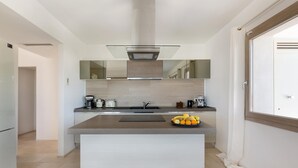 Una cocina moderna con una isla central, horno empotrado y un amplio ventanal.